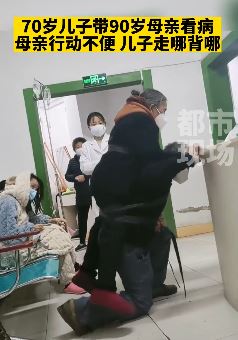 70岁儿子带90岁母亲看病 母亲行动不便儿子走哪背哪