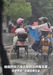 雨天暖心路人脱下身上雨衣送给小女孩