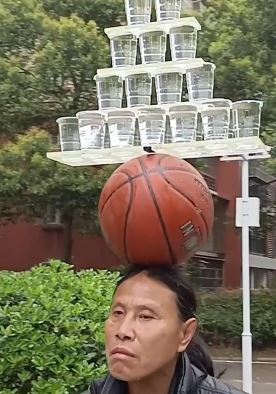 59大叔街头表演头顶篮球再放21杯水  自6岁便开始练习